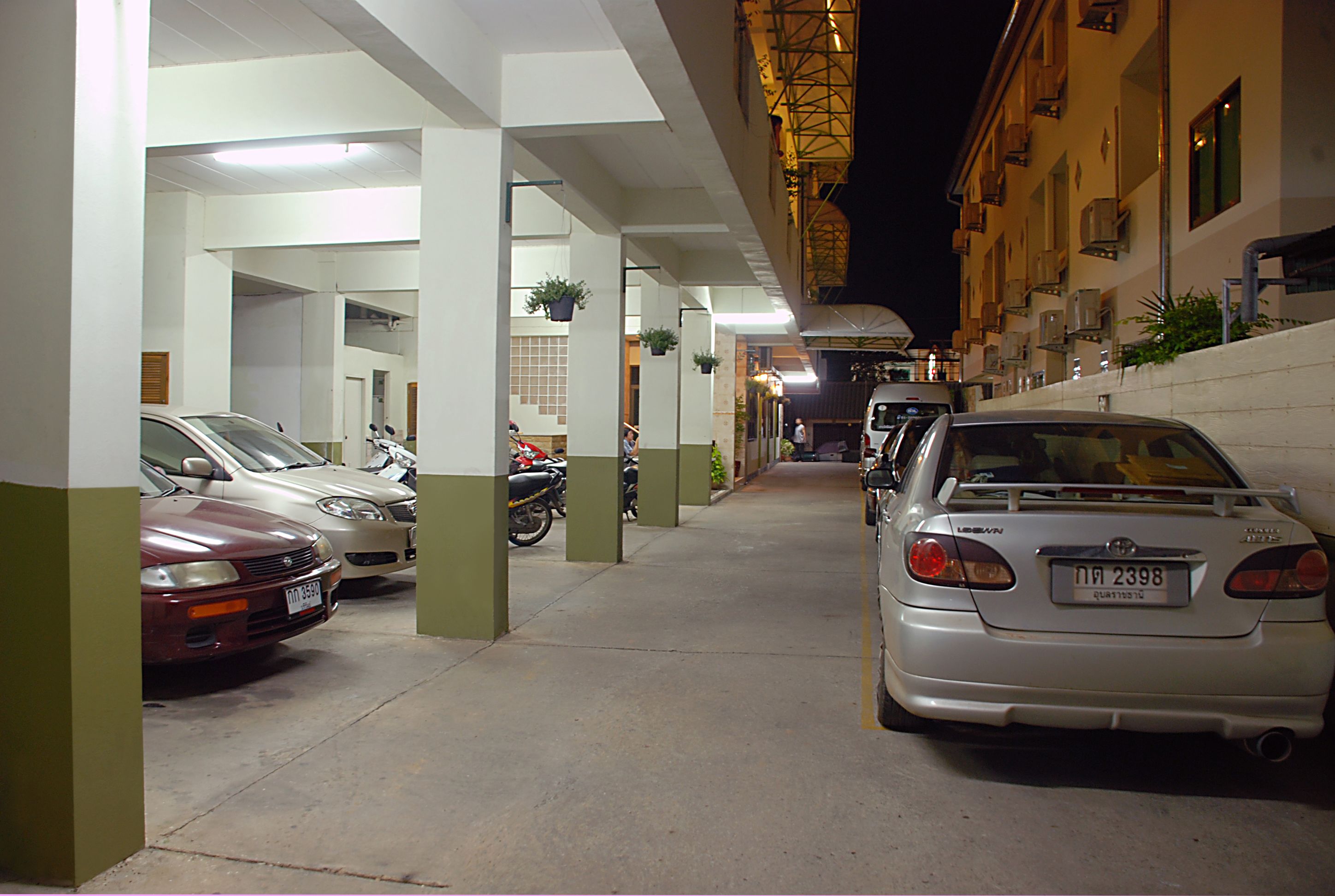 A parking garage with multiple cars and motorcycles parked.