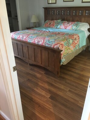 Une chambre à coucher avec un lit en bois, une couvre-lit à motifs et un plancher en bois.