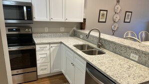 Una cocina moderna con electrodomésticos de acero inoxidable, armarios blancos y encimeras de granito, además de lavavajillas integrado.