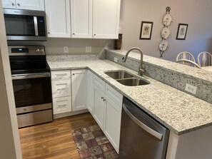Enjoy cooking in this well-equipped kitchen with stainless steel appliances, a granite countertop, and white cabinetry.