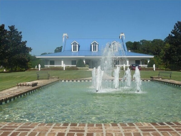 Un grand bâtiment avec un toit bleu et une fontaine au premier plan.