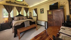 Ein Schlafzimmer mit einem Bett, einer hölzernen Bank, einem Schreibtisch mit Stuhl, einem Fernseher und einer Heizung.