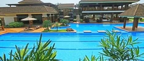 Een buitenzwembad, parasols bij het zwembad en ligstoelen