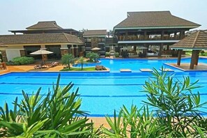 A resort with a central swimming pool, multiple bungalow-style buildings, and outdoor seating areas. - Sta. Maria Homes at One Oasis Cebu Condo (Cebu City)