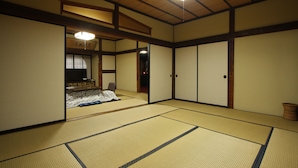 A traditional Japanese room with tatami flooring, sliding doors, and a low ceiling with wooden beams. - Yamadaya Ryokan (Nozawaonsen)
