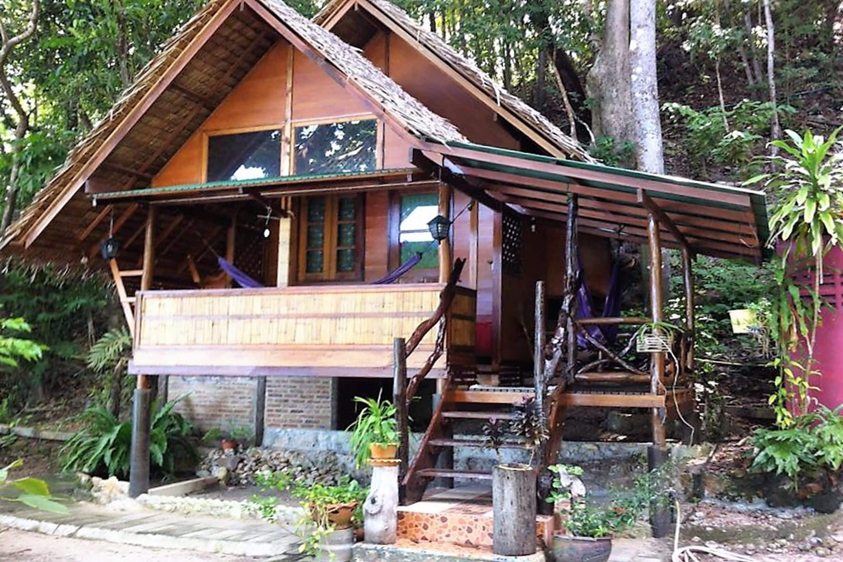 A wooden house with a balcony, surrounded by trees.