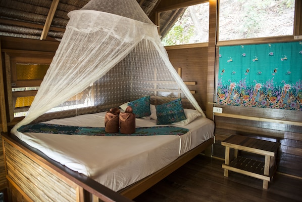 A bed with a canopy, pillows, and a small wooden table beside it. - Sabai Corner Bungalows (Ko Yao)