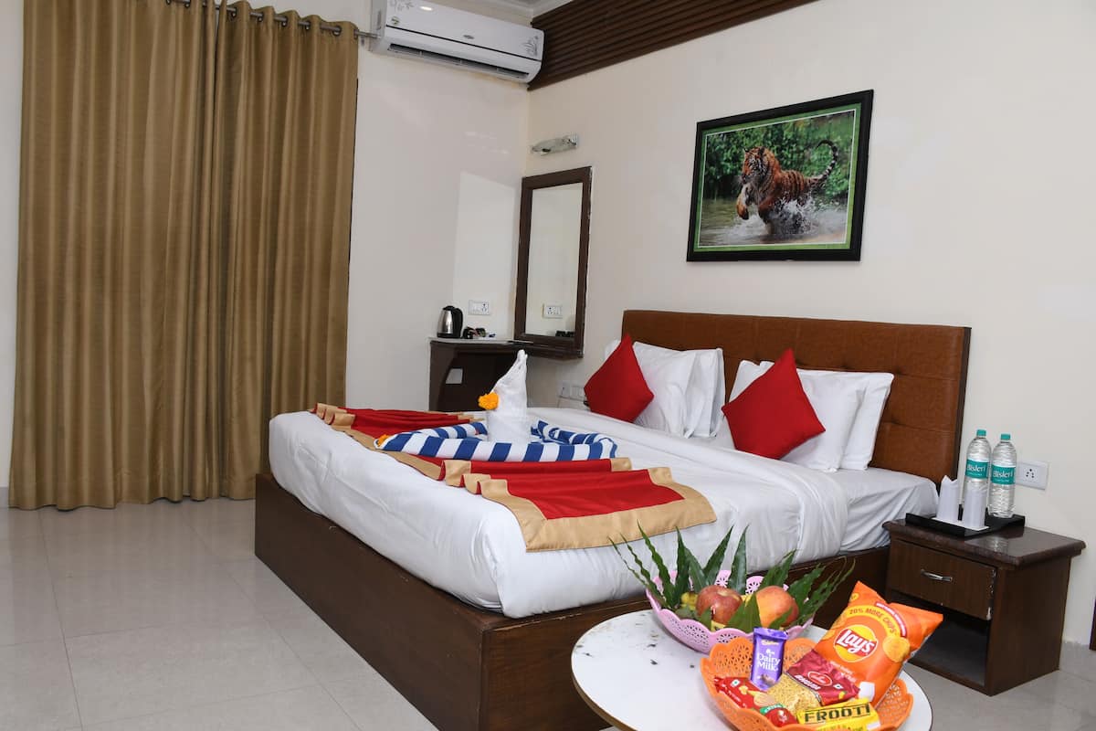Quarto de hotel com cama, mesa de cabeceira com uma garrafa de água, cesta de frutas e espelho na parede.