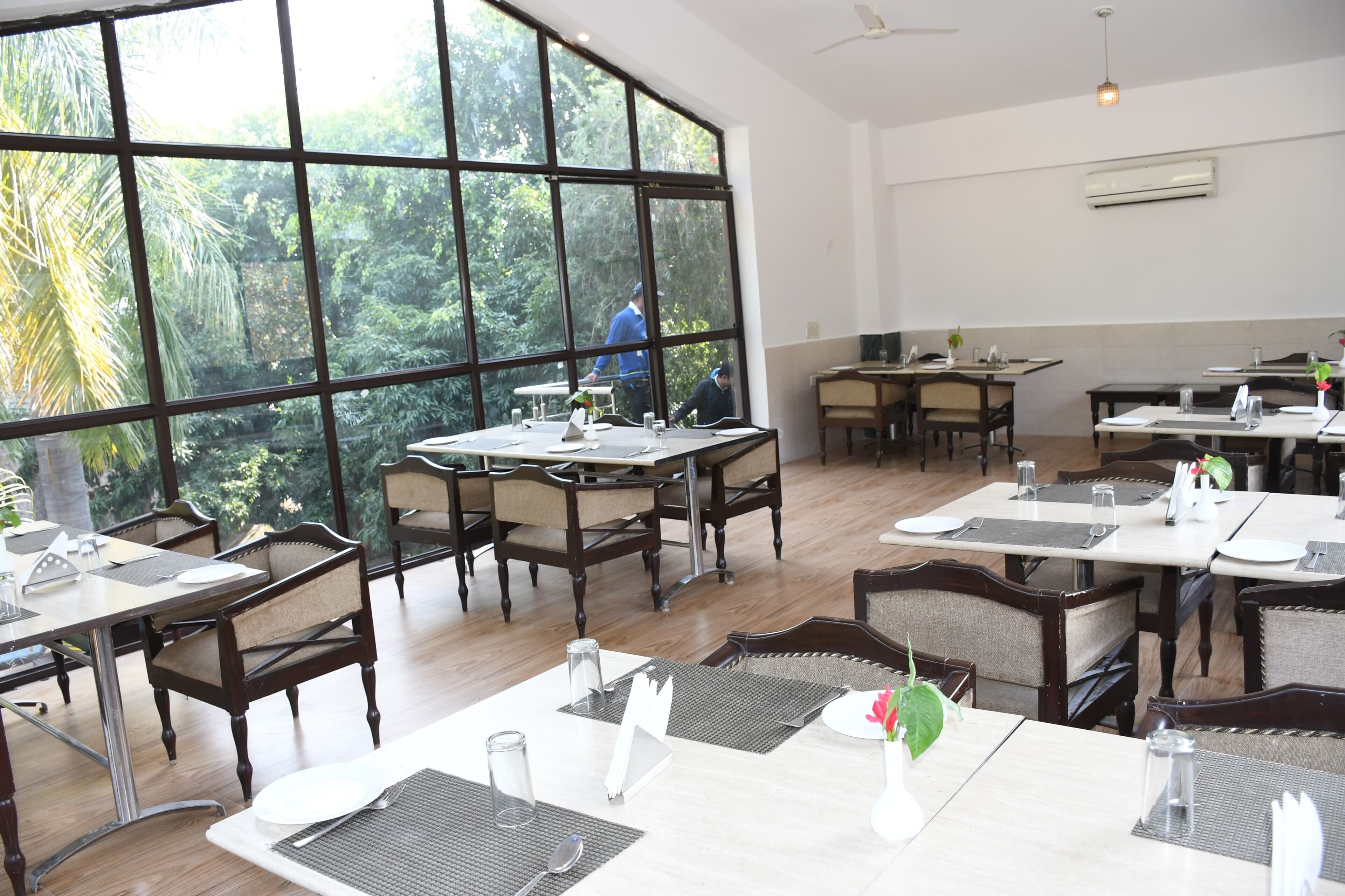 Un restaurante con ventanas amplias, mesas y sillas de madera.