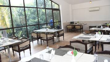 Un restaurante con ventanas amplias, mesas y sillas de madera.