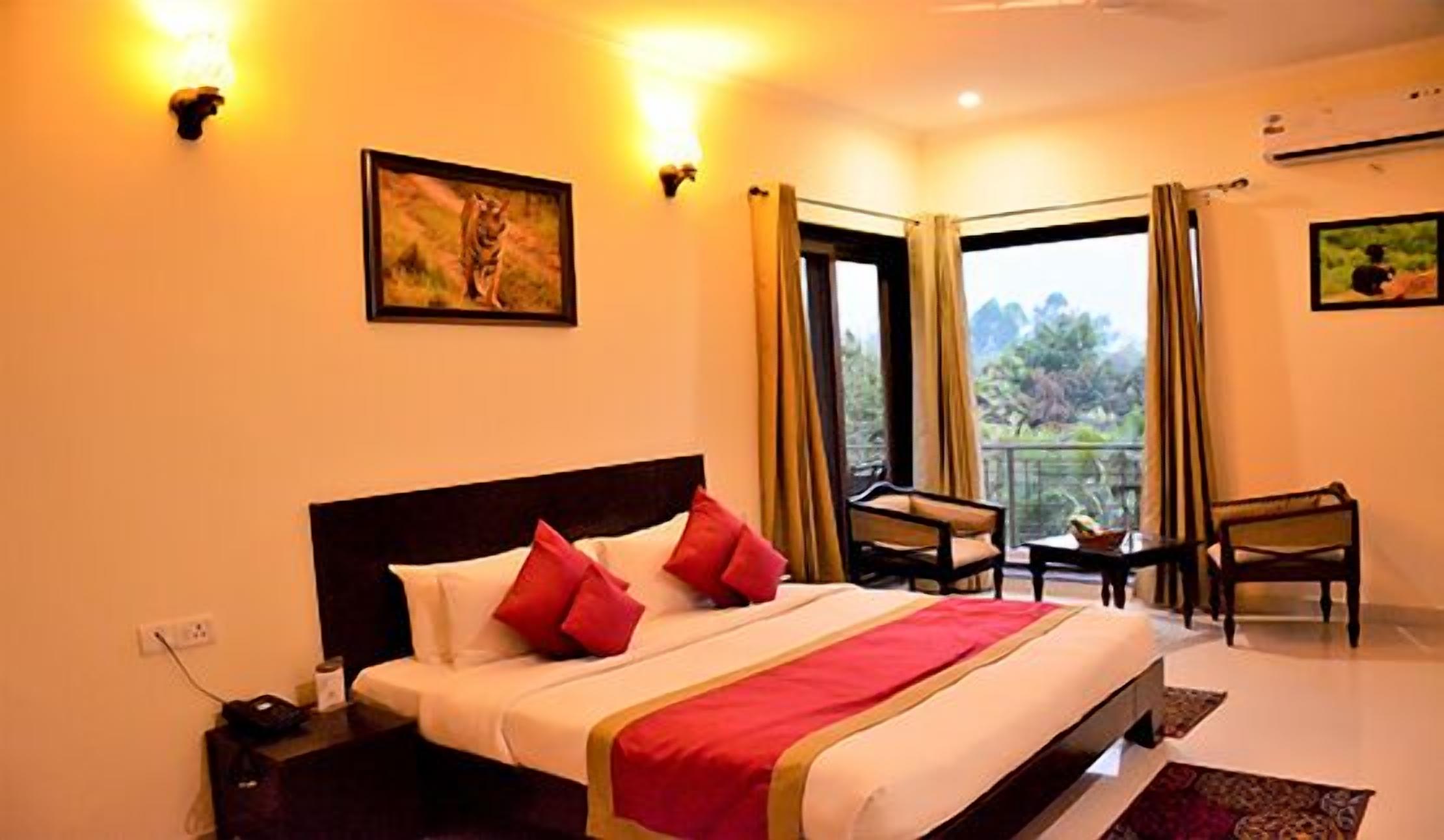 A hotel room with a bed, two chairs, a small table, and a window with curtains.