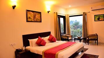 A hotel room with a bed, two chairs, a small table, and a window with curtains.