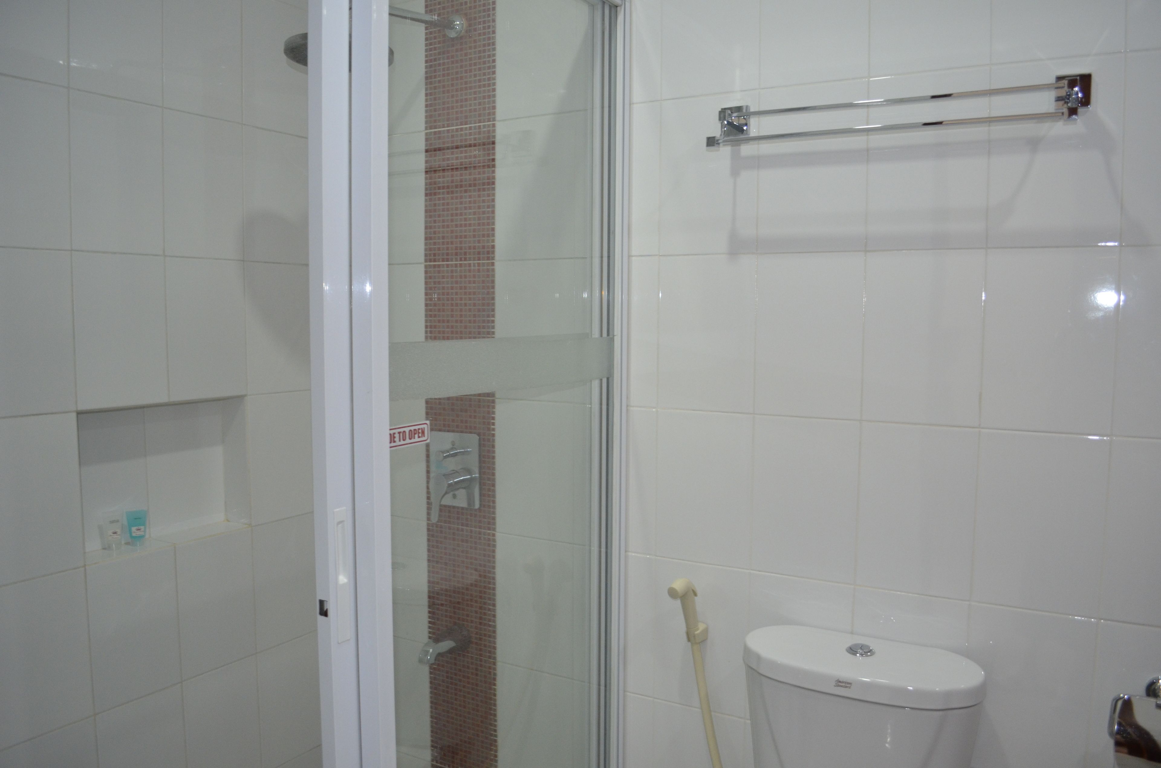 Une salle de bain avec une douche à parois de verre, des toilettes et un porte-serviettes.