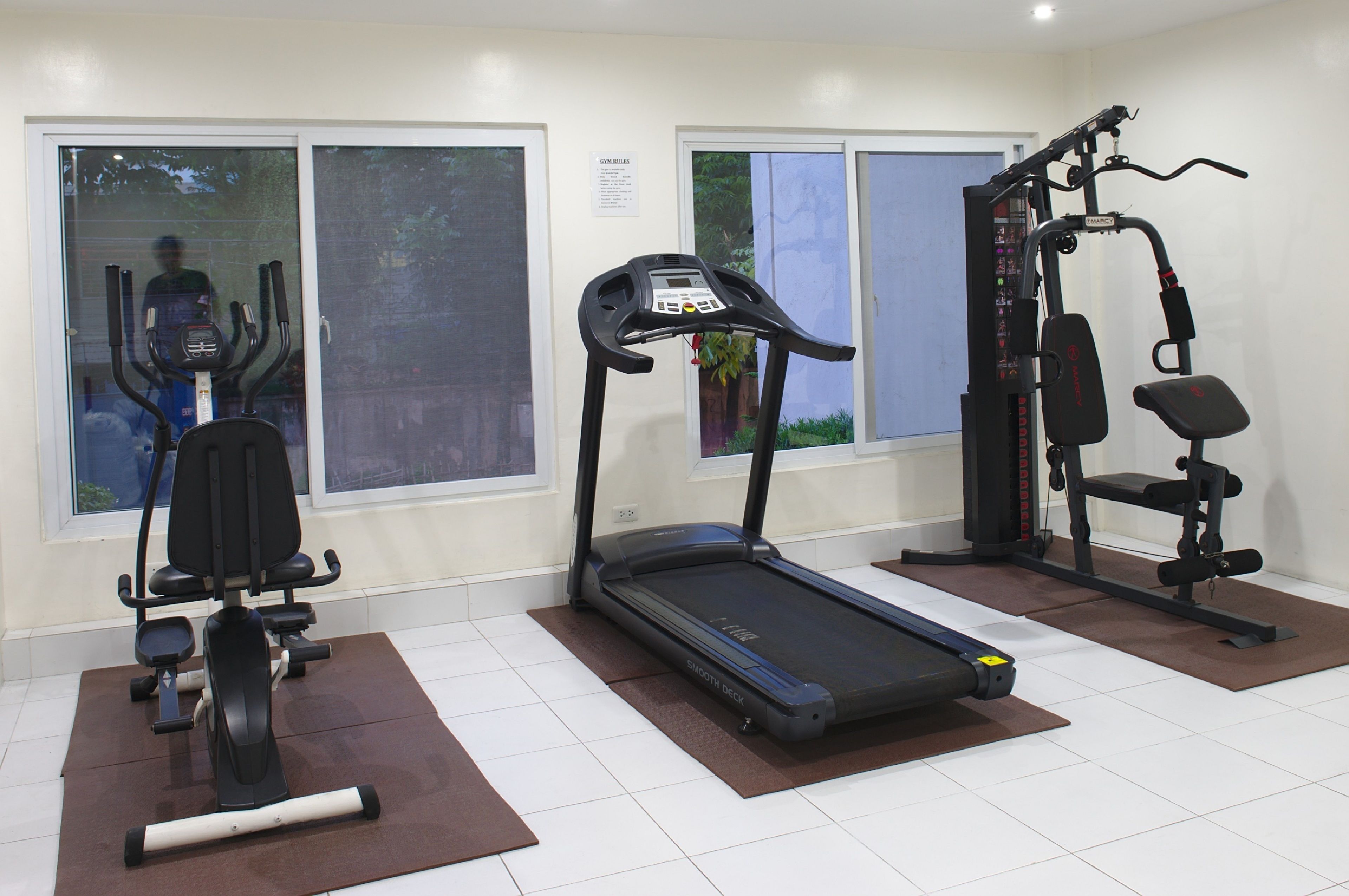 A gym with a treadmill, elliptical, and weight machines.