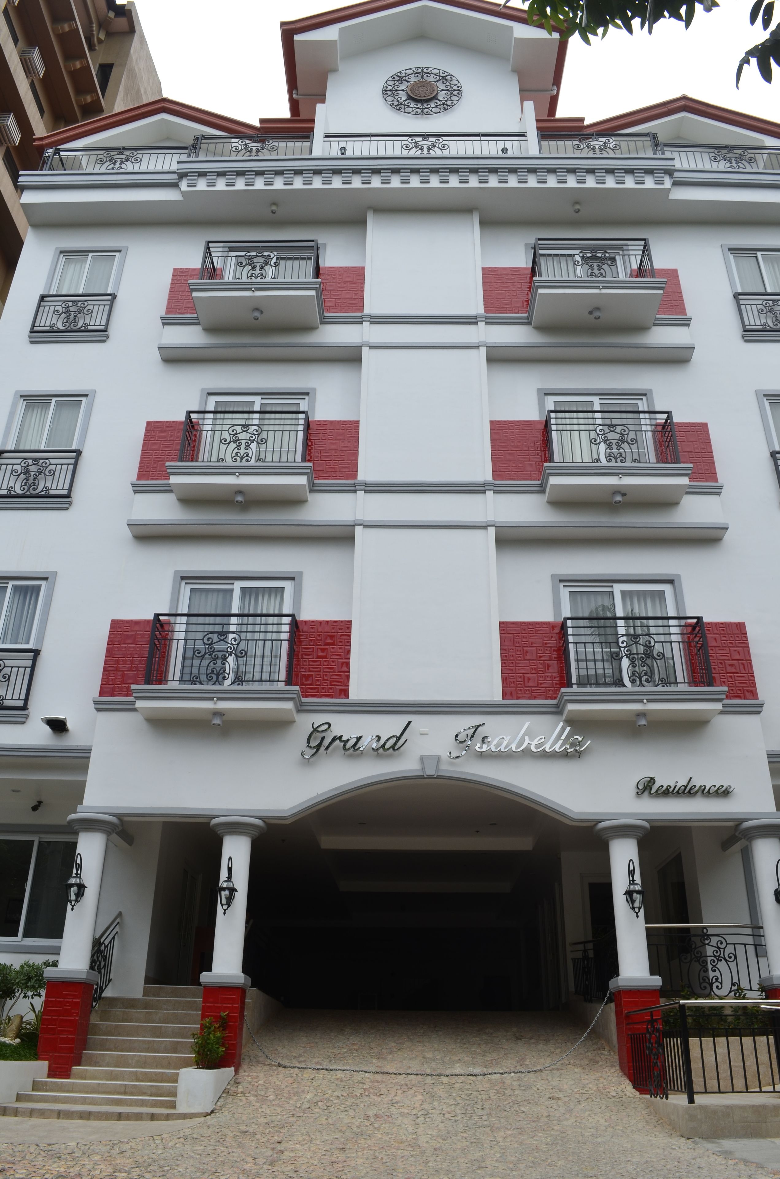 A multi-story hotel with balconies, a grand entrance, and a sign reading "Grand Isabella Residence".