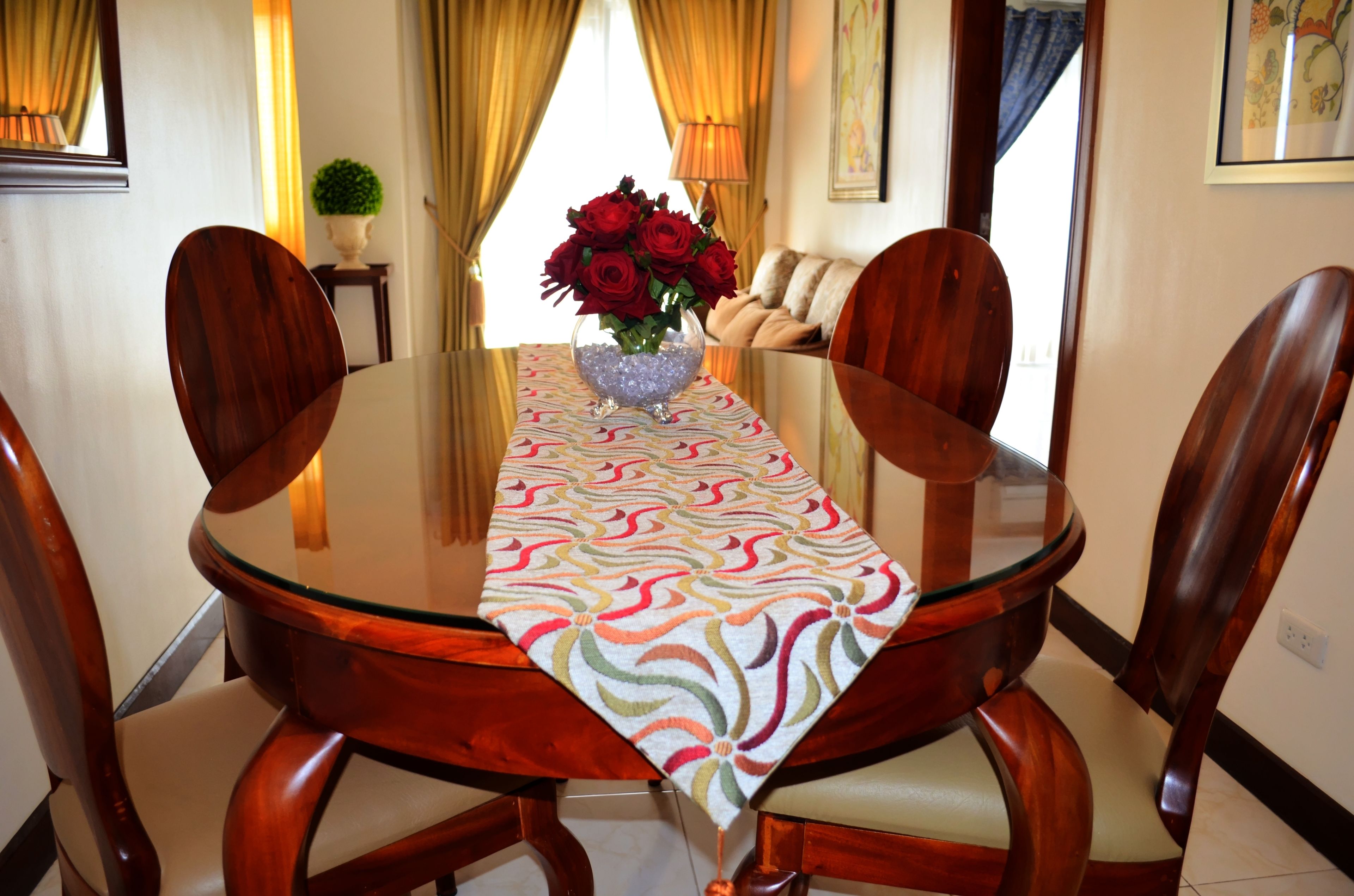 Une table à manger recouverte d’une nappe à motifs, entourée de chaises en bois dotées d’assises rembourrées.