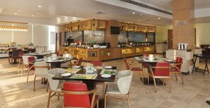 Un restaurant moderne doté d’un bar central, de plusieurs tables et chaises, et d’un sol à motifs.
