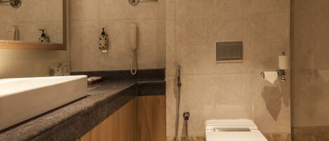 A modern bathroom with a large sink, mirror, toilet, and shower.