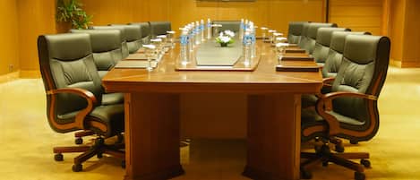 A conference room with a long table, multiple chairs, water bottles, and a plant.