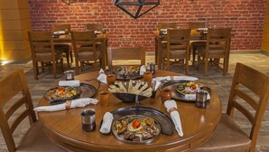 A dining area with a brick wall, wooden tables, and chairs. - Lemon Tree Premier Patna (Patna)