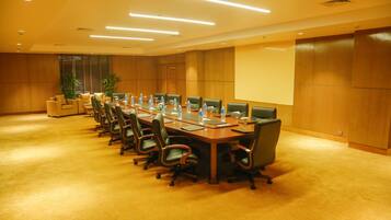 A conference room with a long table, multiple chairs, water bottles, and a projector screen.