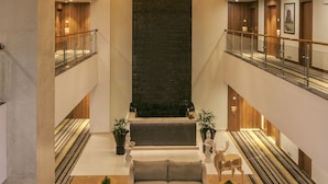A spacious lobby with a high ceiling, multiple floors, and a central seating area with sofas and a coffee table. - Lemon Tree Premier Patna (Patna)