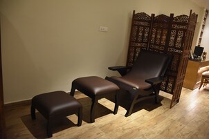 Una habitación con piso de madera, una silla marrón oscuro y un reposapiés a juego.