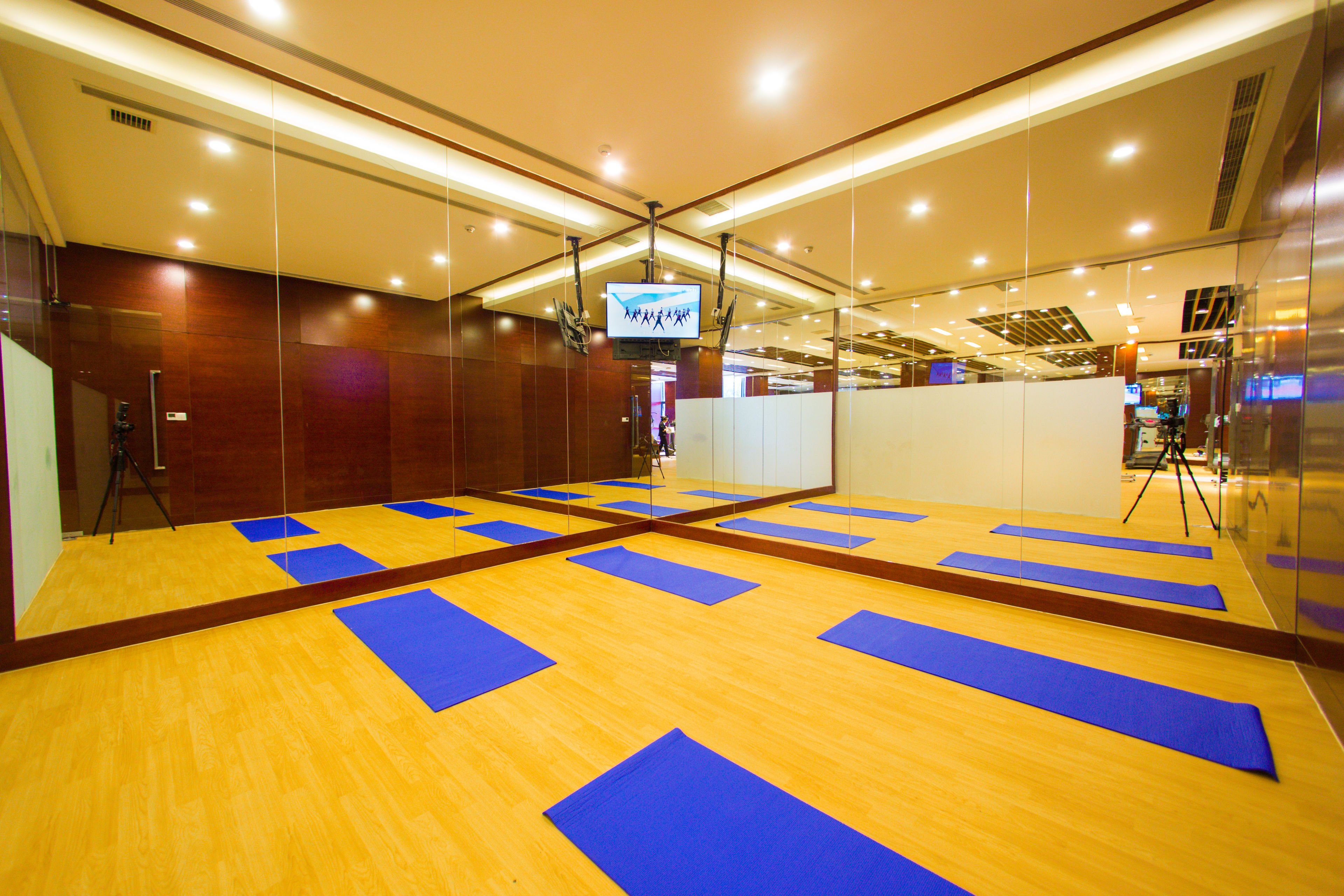 A spacious room with a wooden floor and blue mats arranged for activities.