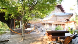A wooden deck with a hammock, a wooden bench, and a table.