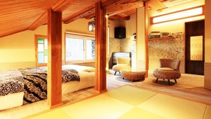 A traditional Japanese-style room with tatami flooring, a low wooden ceiling, and a bed with a patterned bedspread.