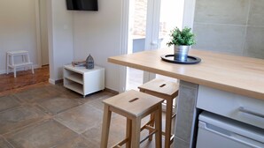 A modern kitchen with a wooden countertop, two stools, a small white cabinet, and a potted plant. - Lisbon Beach Apartments 2. Beach 500 Mts, terrace, barbecue, pets welcome. (Costa da Caparica)