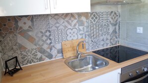 A kitchen with a stainless steel sink, a wooden cutting board, a black stand, and a patterned backsplash. - Lisbon Beach Apartments 2. Beach 500 Mts, terrace, barbecue, pets welcome. (Costa da Caparica)