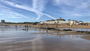 Ein Strand mit Menschen, Gebäuden und einem klaren Himmel.