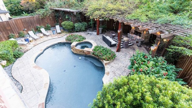 A backyard with a swimming pool, patio furniture, and a pergola with string lights. - Modern Tudor with Pool & Backyard Oasis on the M Streets in the Heart of Dallas (Dallas)