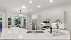 A modern kitchen with white cabinetry, a marble island, stainless steel appliances, and a chandelier. - Modern Tudor with Pool & Backyard Oasis on the M Streets in the Heart of Dallas (Dallas)