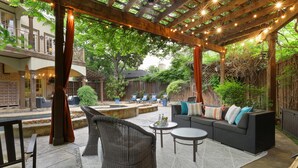 An outdoor patio with wicker furniture, a stone floor, and string lights. - Modern Tudor with Pool & Backyard Oasis on the M Streets in the Heart of Dallas (Dallas)
