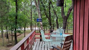 A wooden deck with metal chairs and a table, surrounded by trees. - Treehouse Cabin/ Beach and Lake Access (Pottsboro)