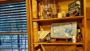 A wooden shelf with various items including a map, candles, and a sign that reads "Delicious & Fresh." - Treehouse Cabin/ Beach and Lake Access (Pottsboro)