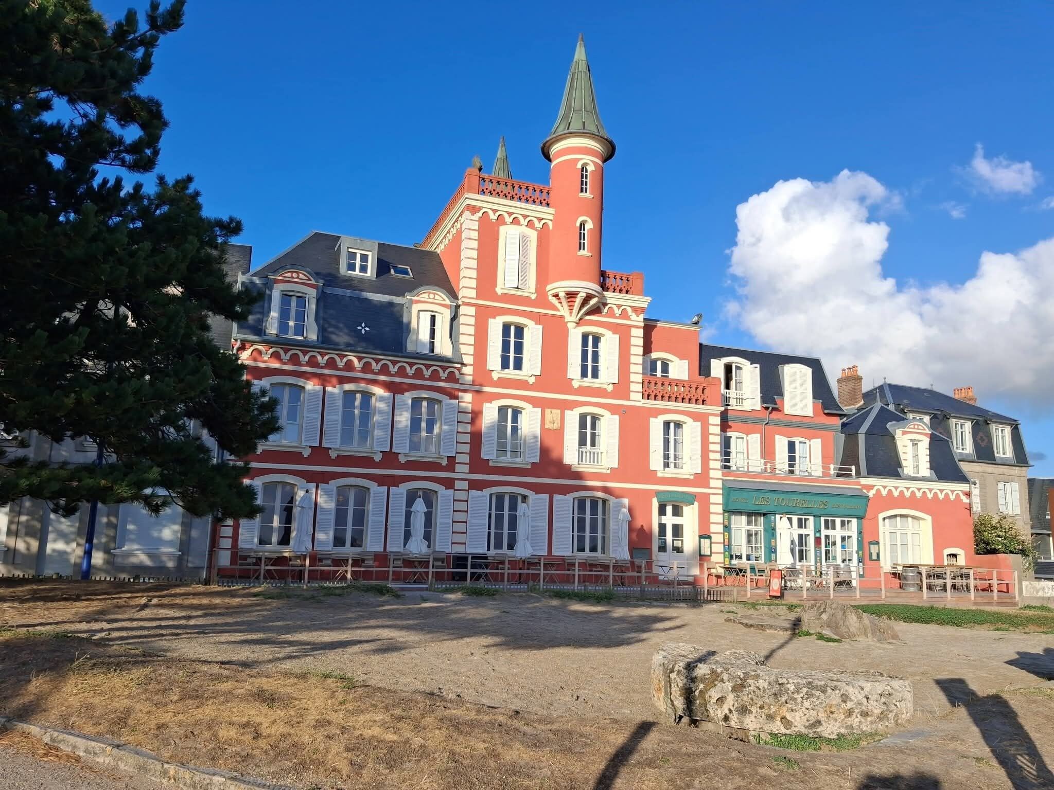Een historisch gebouw met meerdere verdiepingen, een opvallende toren en een balkon met witte hekwerken.