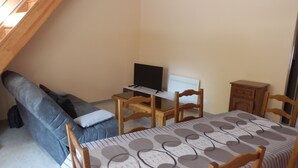 Une petite pièce comprenant un canapé, une table avec un téléviseur, une chaise et un meuble.