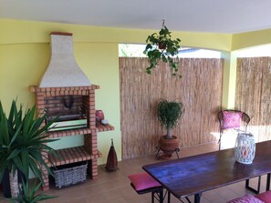 Ein Patio mit Backofen, Tisch, Stühlen und Topfpflanzen.
