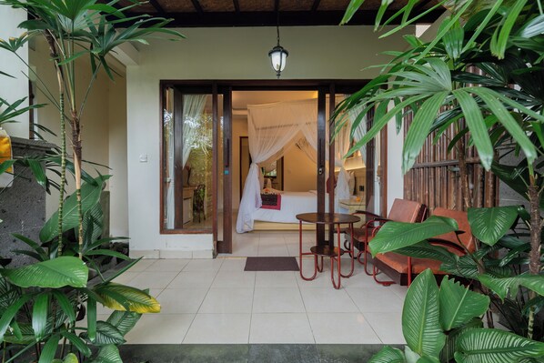 Una habitación con una cama, una mesa y sillas, rodeada de plantas.