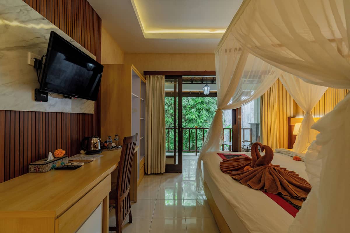 A hotel room with a bed, a desk, a television, and a balcony with curtains.