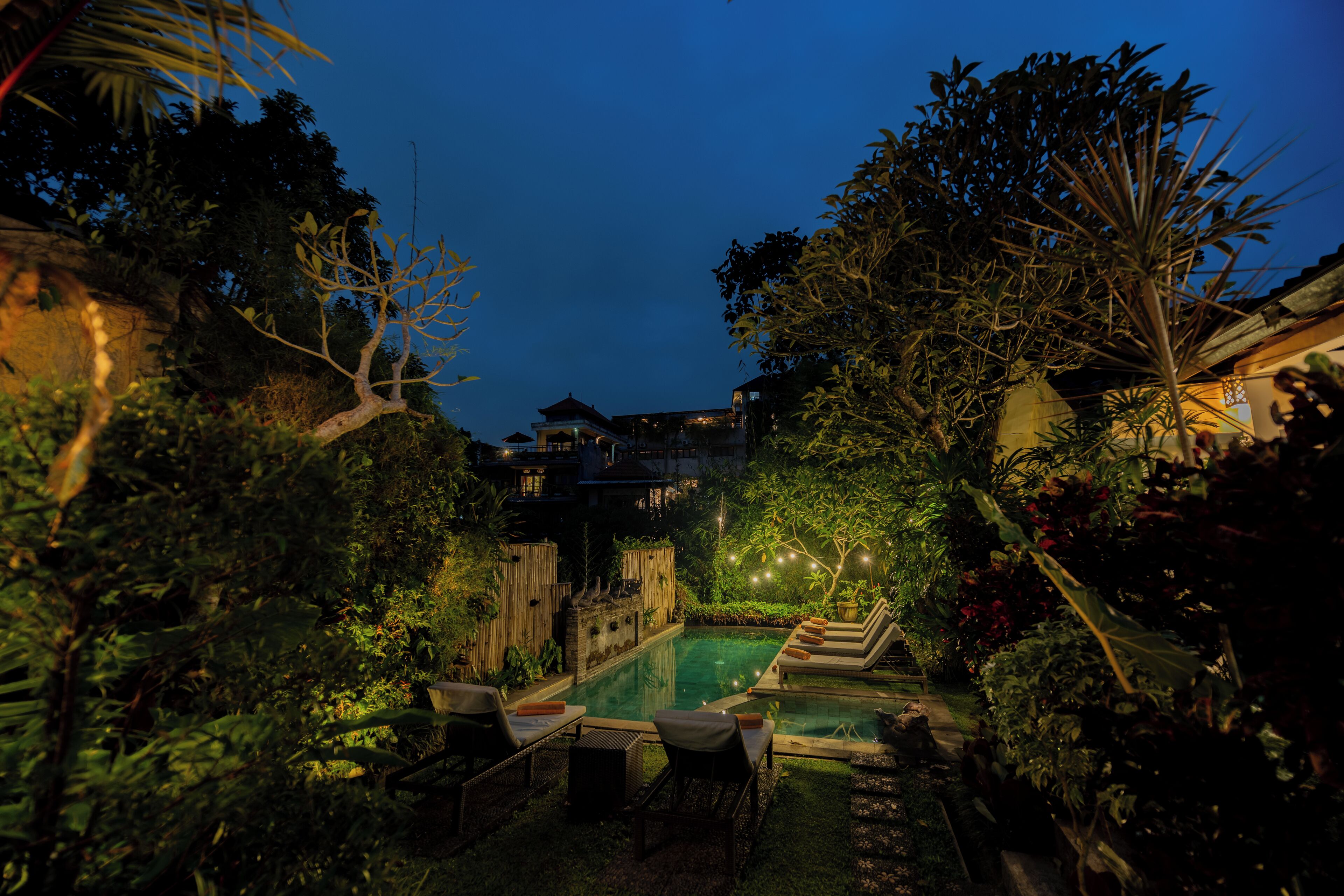 A pool area with lounge chairs and a wooden fence.