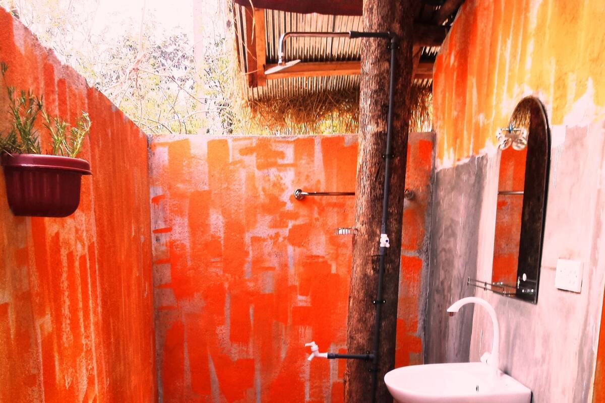 A bathroom with a white sink, a shower, and a red wall.