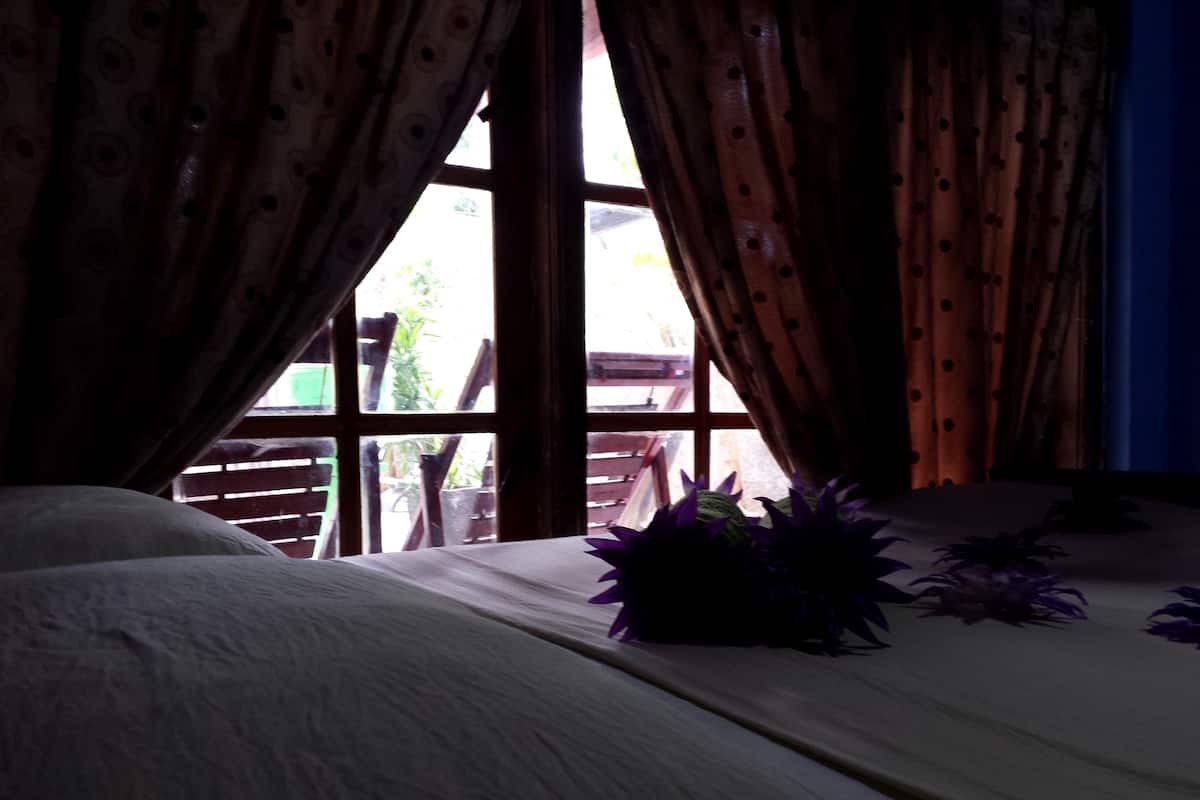A room with a bed, a window, and a view of the outside.