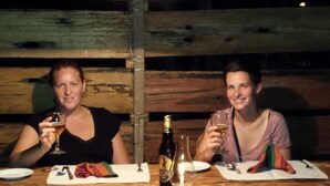 Two people sitting at a wooden table with plates, cutlery, and a bottle of wine. - Greenwood Udawalawa Safari Resort (Udawalawa)