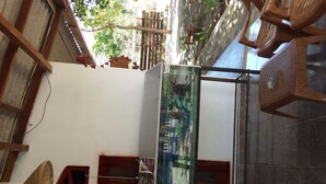 A room with a wooden ceiling, a window with a view of trees, and a wall-mounted air conditioner. - Greenwood Udawalawa Safari Resort (Udawalawa)