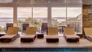 Ein Poolbereich mit Liegestühlen und Blick auf das Meer.