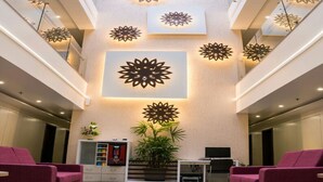 A lobby with a central seating area, a vending machine, a television, and decorative wall art.